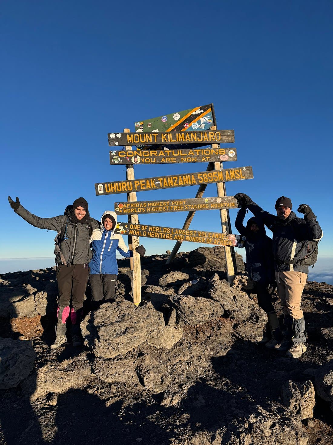 Resenärer firar vid toppskylten på Kilimanjaro