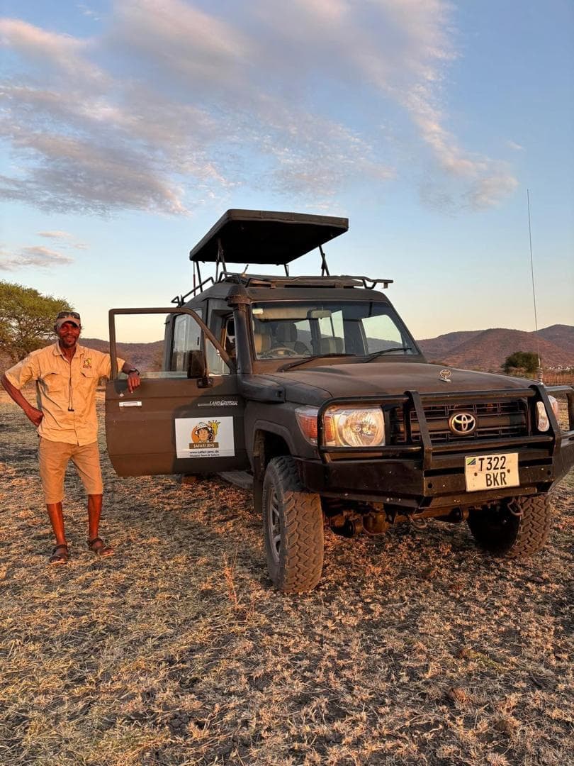 En guide står vid en safaribil i gryningen