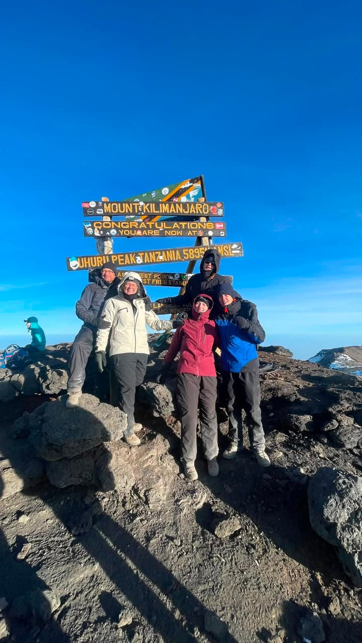 Resenärer vid toppskylten på Kilimanjaro