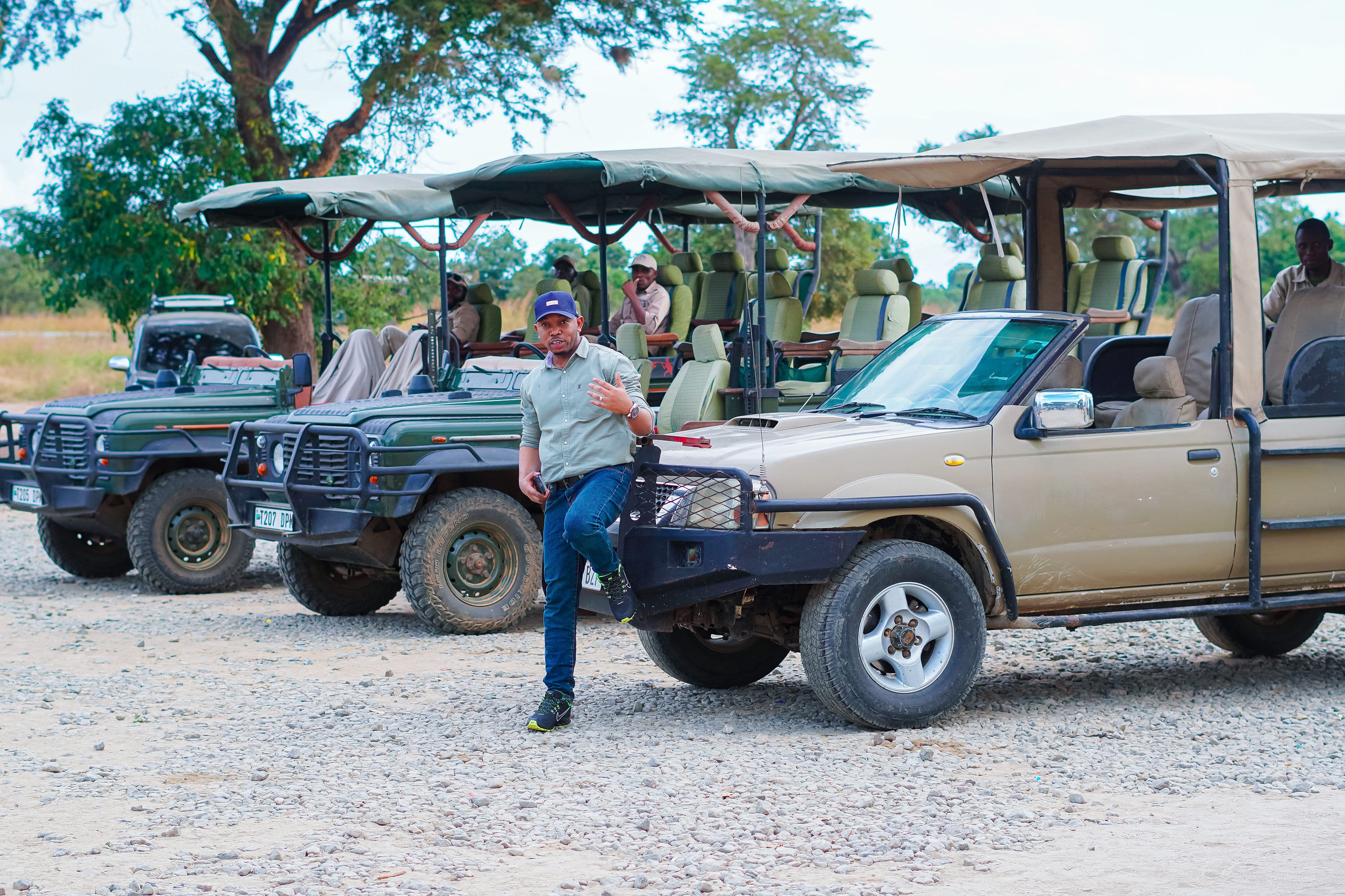 En guide bredvid en rad safaribilar