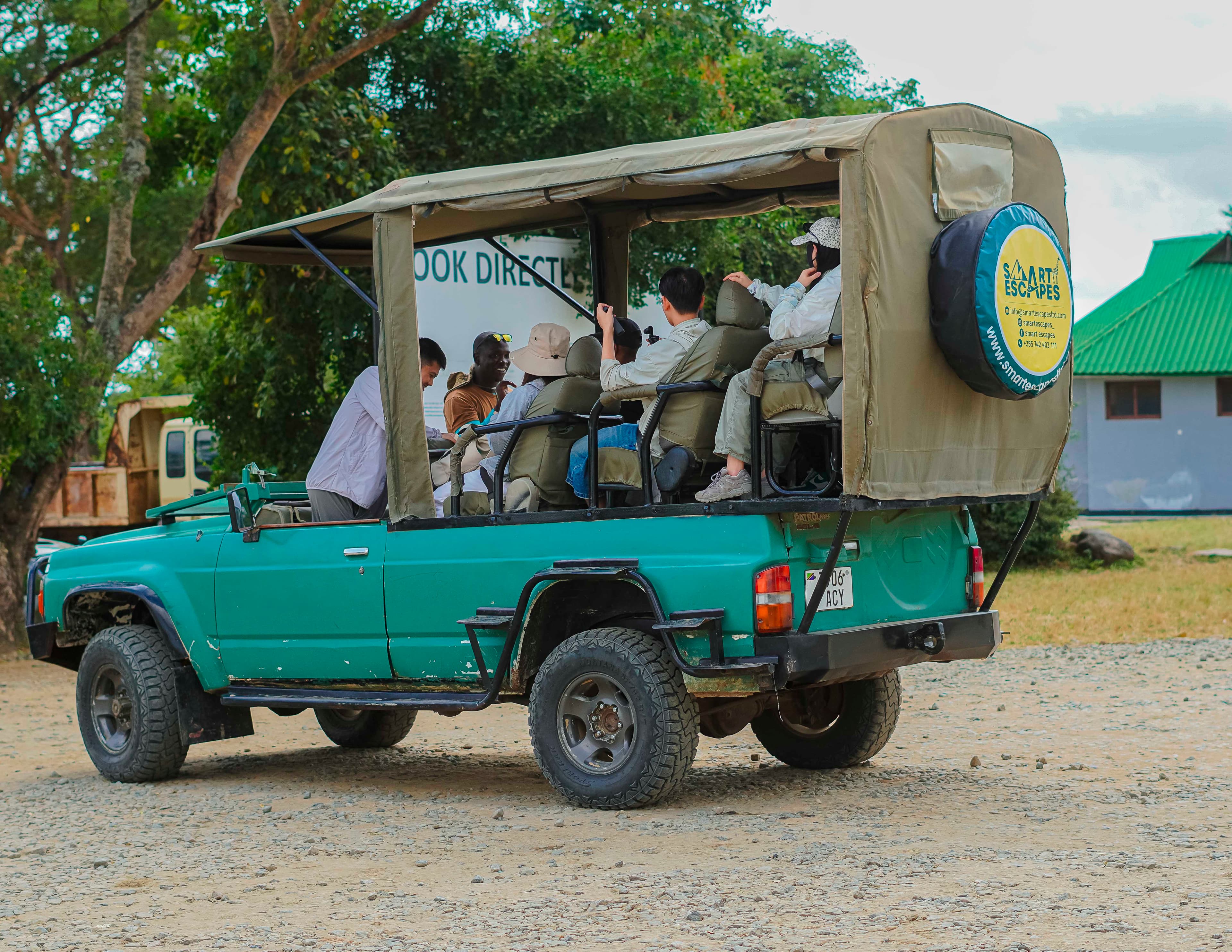 Resenärer i en grön safaribil med Smart Escapes logotyp
